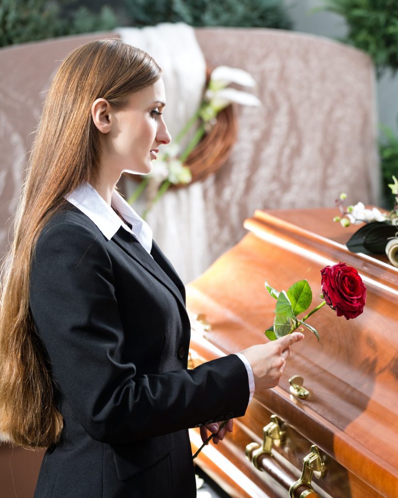 Mourning Woman at Funeral with coffin Mourning woman on funeral with red rose standing at casket or coffin